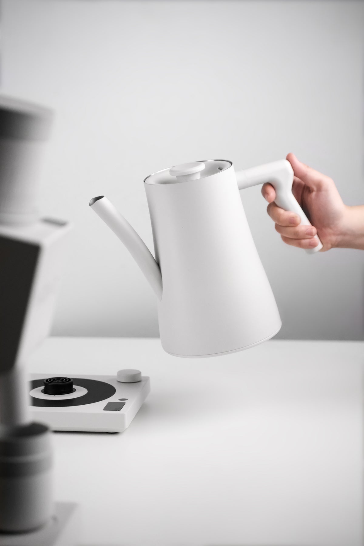 Lifting the white AURA 1.5 L FLUX kettle by its angular handle