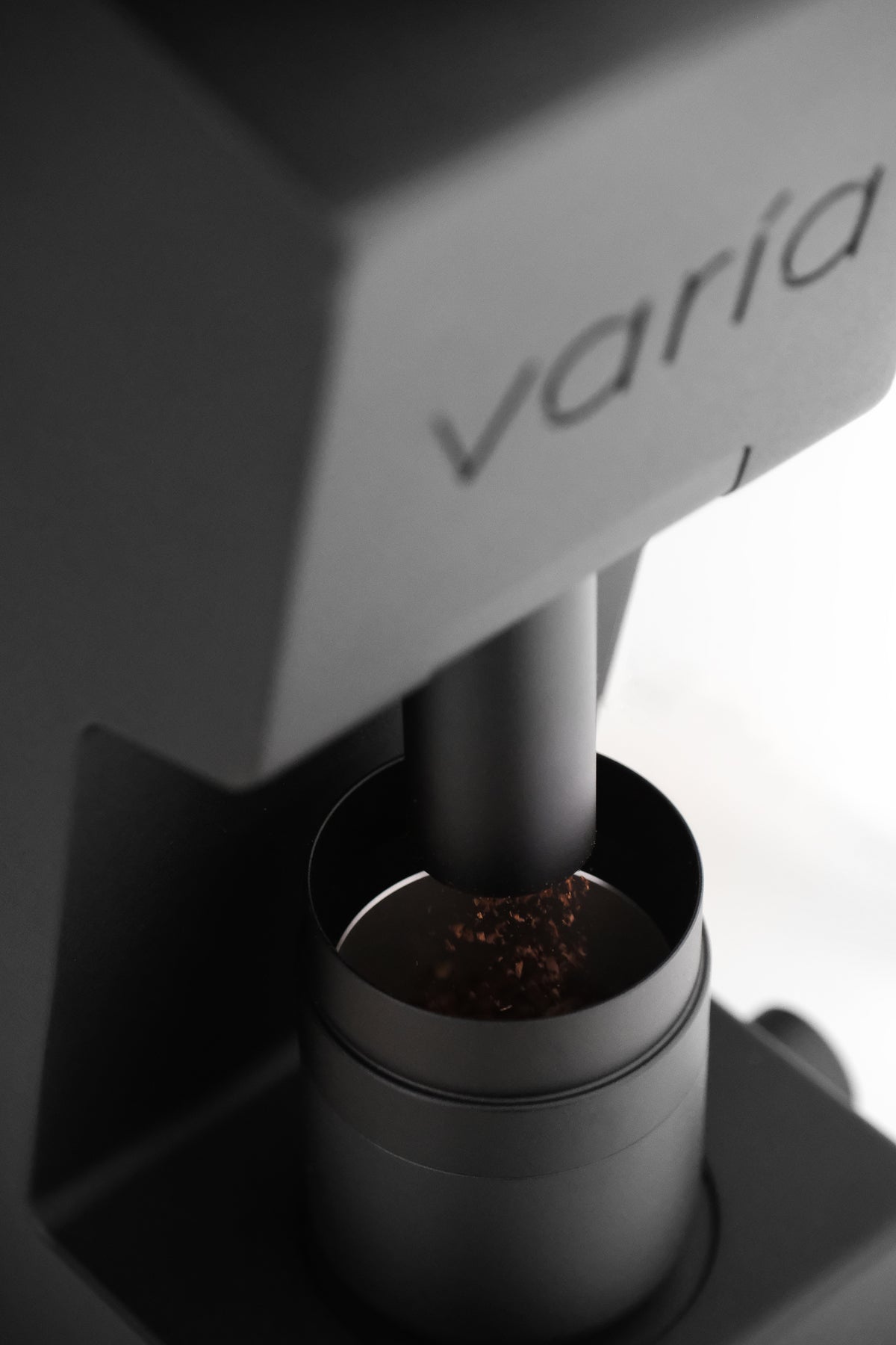 Freshly ground coffee falling from a black Varia VS6 into its dosing cup