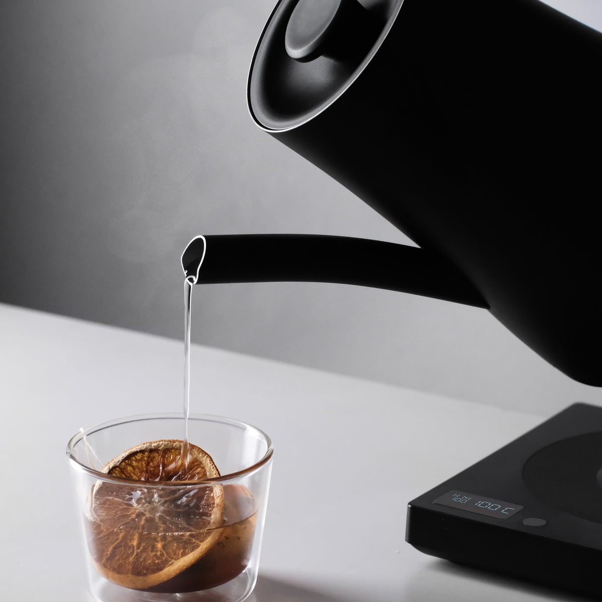 Pouring tea from the short spout of the black AURA 1.5 L kettle